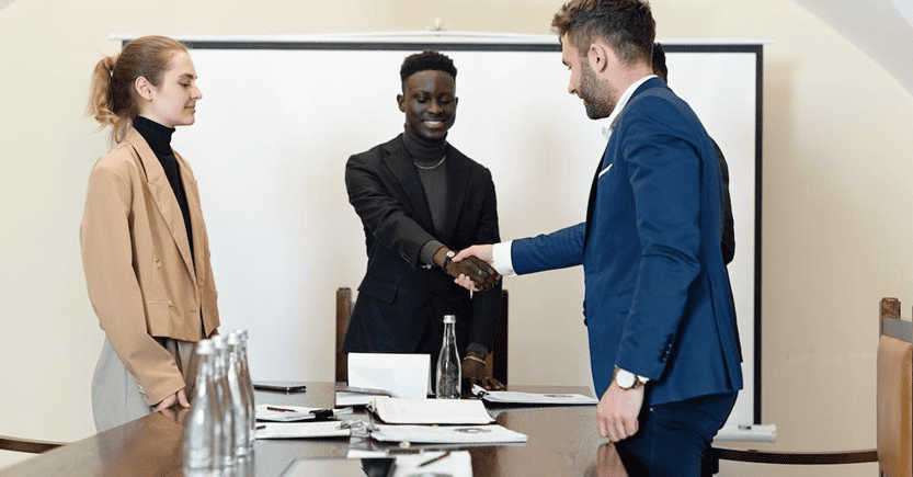Business handshake during financial negotiation | eFinancialModels Business professionals shaking hands in a meeting setting.